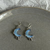 Pair of stainless steel hoop earrings shaped like crescent moons with a blue iridescent finish