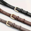 Deux ceintures en cuir marron et noir avec des boucles dorées, montrées en diagonale sur fond blanc.
