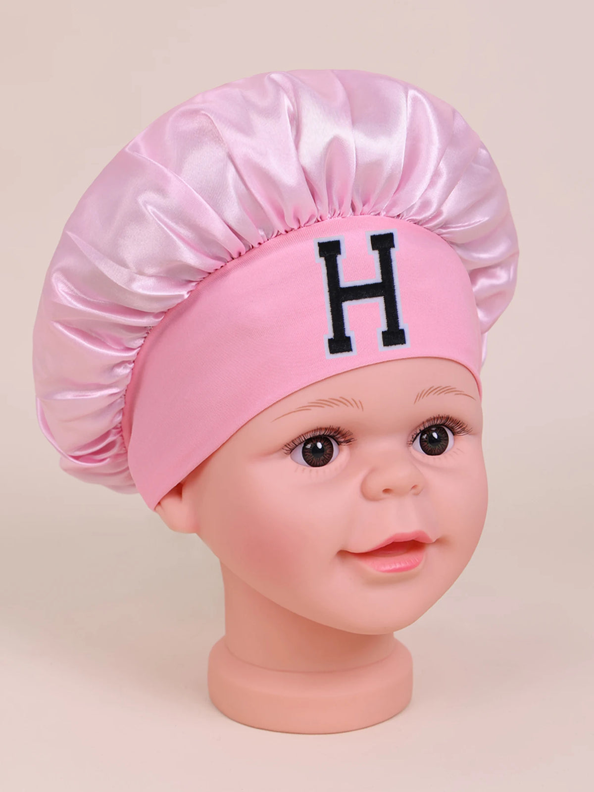 Pink satin sleep cap for kids with a black letter H