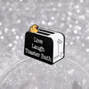 A black enamel pin featuring a yellow duck on a loaf of bread with the text Live Laugh Toaster Bath