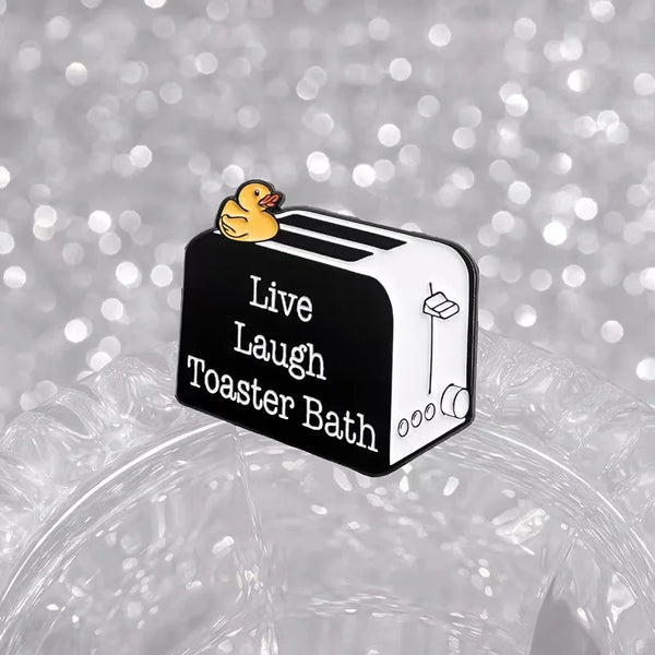 Broche émaillée noire avec un canard jaune sur une miche de pain, texte Live Laugh Toaster Bath