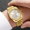 A gold-toned wristwatch with a clear face and rhinestone accents is worn on a person's wrist.