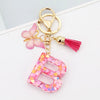 Gold alphabet letter keychain featuring a pink butterfly charm and a magenta tassel