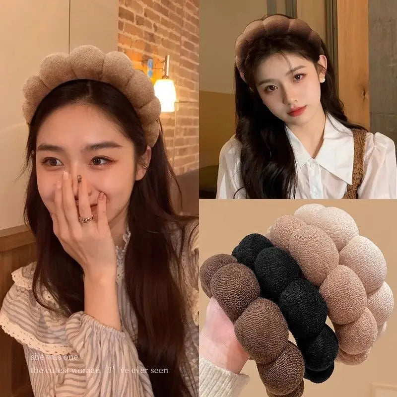 A close-up of beige and black cloud sponge hair accessories headbands displayed on a wooden surface.