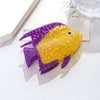 Pinza para el pelo con forma de pez de plástico en colores morado y amarillo