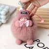 A pink fluffy plush doll with a knitted hat and a bow is shown being held, featuring an HDSP keychain.