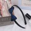 A dark blue grosgrain ribbon hair bow is displayed next to a box and a glass bottle.