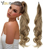 A model shows off long, blonde synthetic wrap around hair extensions in a loose wavy style.