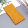 A rectangular mustard yellow PU leather storage bag lying on a gray surface next to some books.