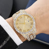 Montre de couleur or avec une lunette et un bracelet incrustés de diamants portée au poignet.