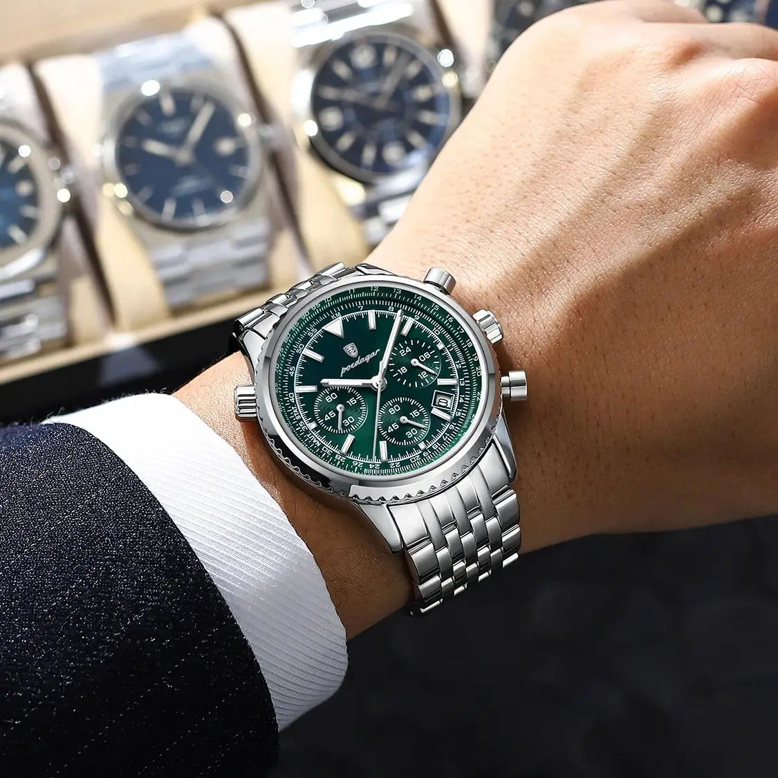 Primer plano de un reloj cronógrafo de lujo para hombre con esfera verde y caja de plata, usado en una muñeca.