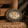 A vintage western belt buckle with a gold-toned design resting on a brown wooden surface.