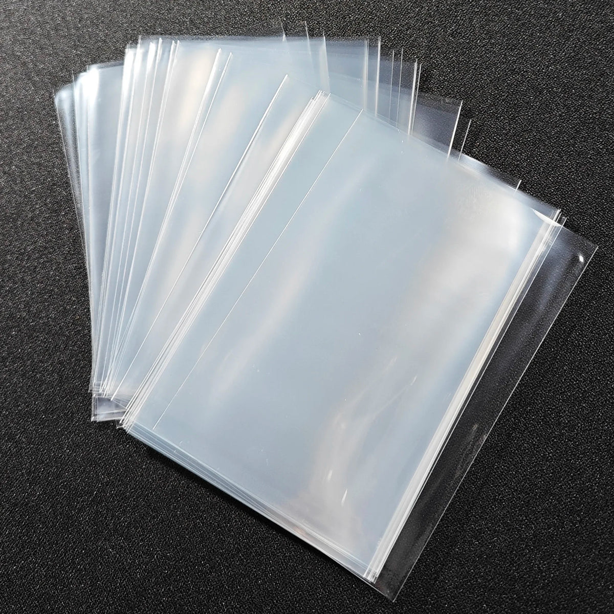 A stack of premium clear card sleeves for sports collectibles, showing various transparent plastic sleeves.