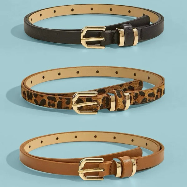 A set of three belts in black, leopard print, and tan leather with brass buckles.