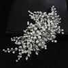 A delicate bridal headpiece featuring white pearls and clear rhinestones arranged in a floral spray.