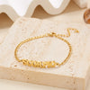 A gold stainless steel zodiac constellation charm bracelet with the word SCORPIO resting on a light beige stone.