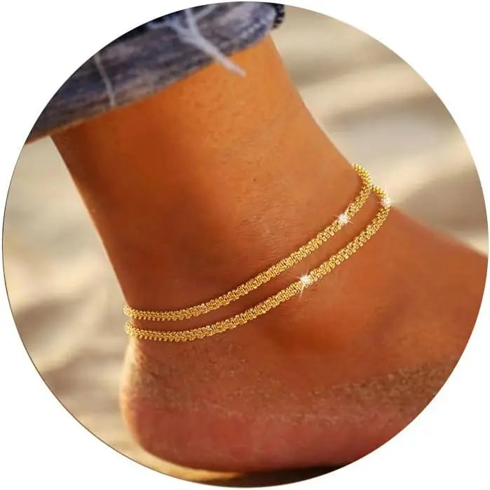 Gold plated glitter layered anklets worn on a person's ankle.