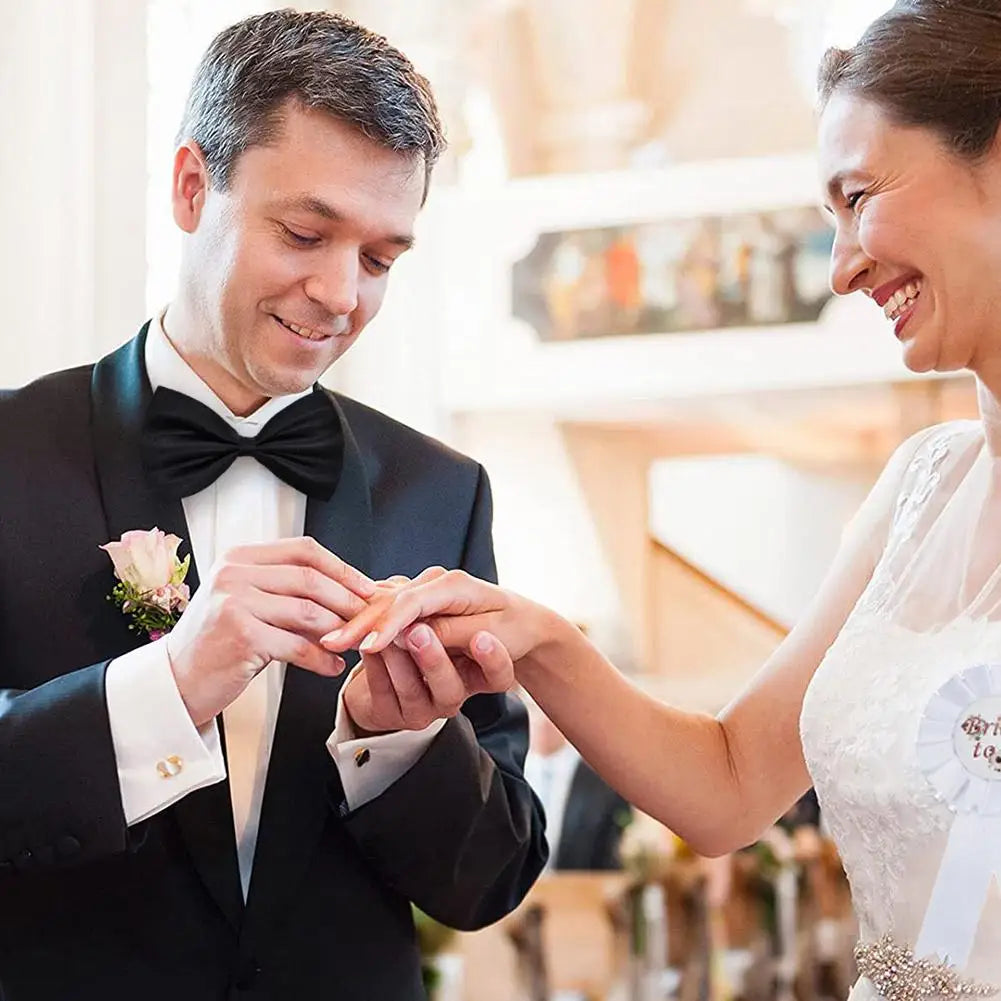 A man and a woman are joining hands during a wedding ceremony, with the man wearing a black tuxedo.