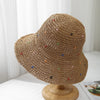 Vista cercana de un sombrero de paja panameña tejido a crochet con adornos coloridos sobre un soporte de madera.