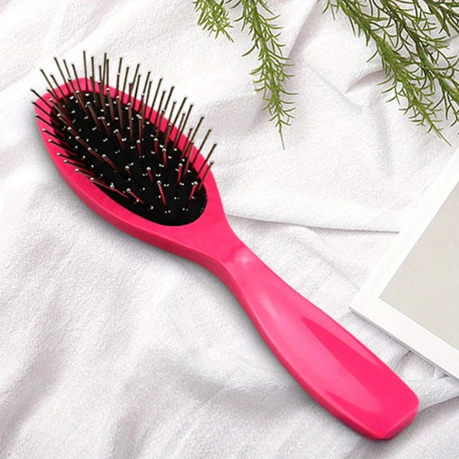 A pink anti-static steel comb hair brush with black bristles is shown on a white towel.