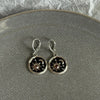 Silver hoop earrings featuring a black disc design with a gold sun and crescent moon motif.