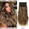 Extensiones largas y onduladas de cabello castaño claro con detalle de clip-in negro