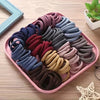A collection of various colored boho seamless elastic hair ties arranged on a pink tray.