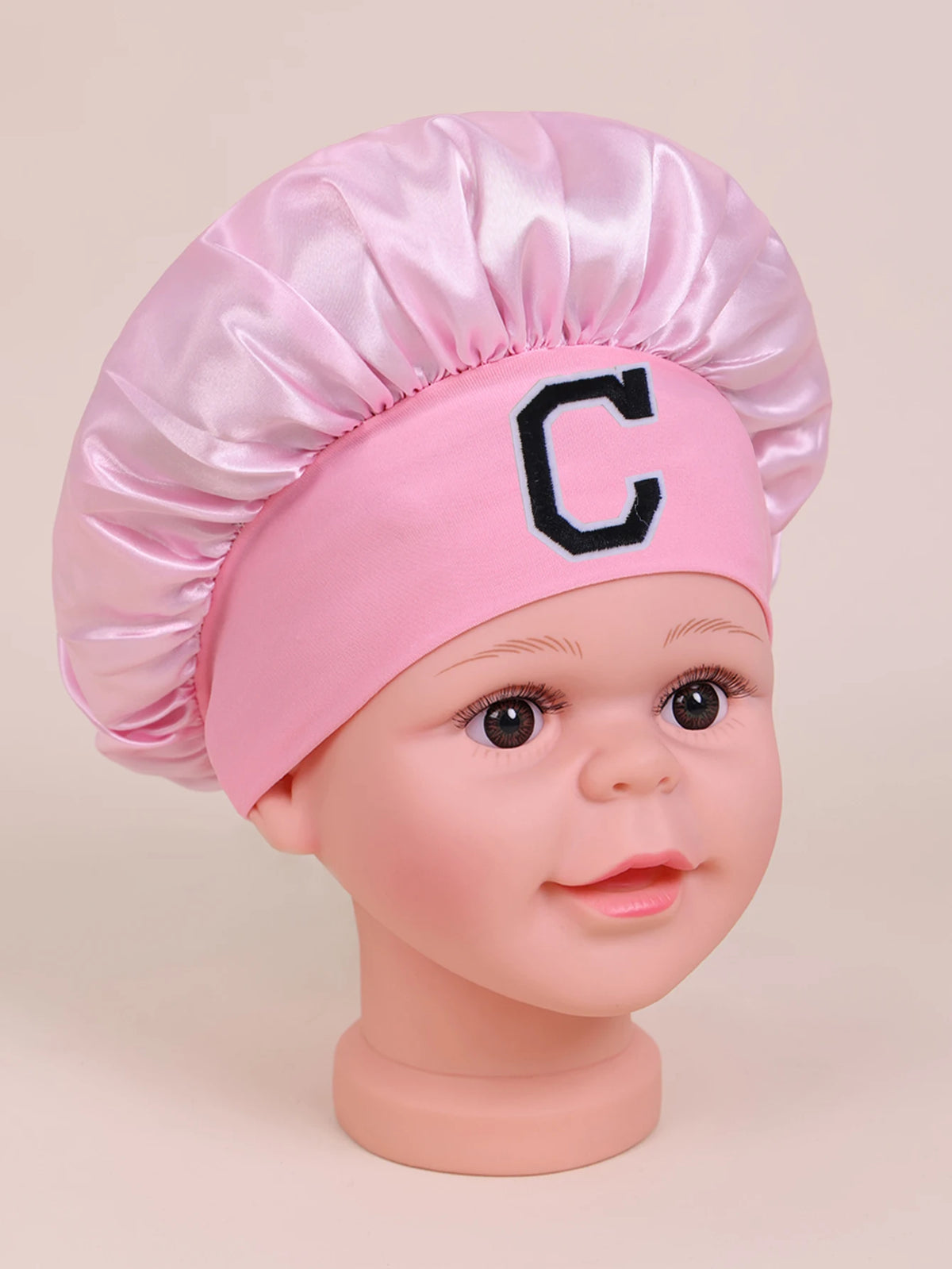 Pink sleep cap for kids with a black letter C embroidered on the front