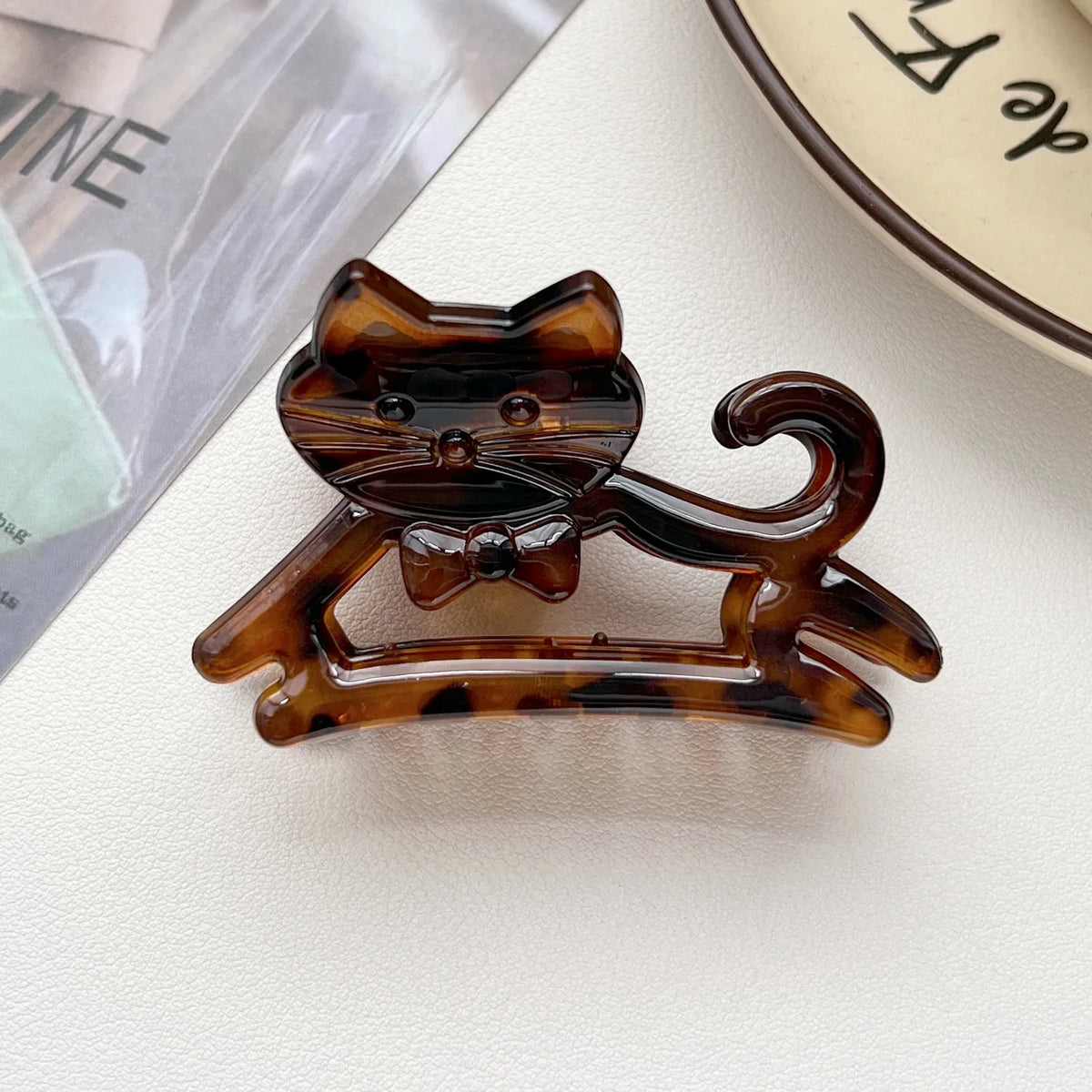 A set of cute cartoon animal hair clips shaped like cats, made of glossy amber-colored material.