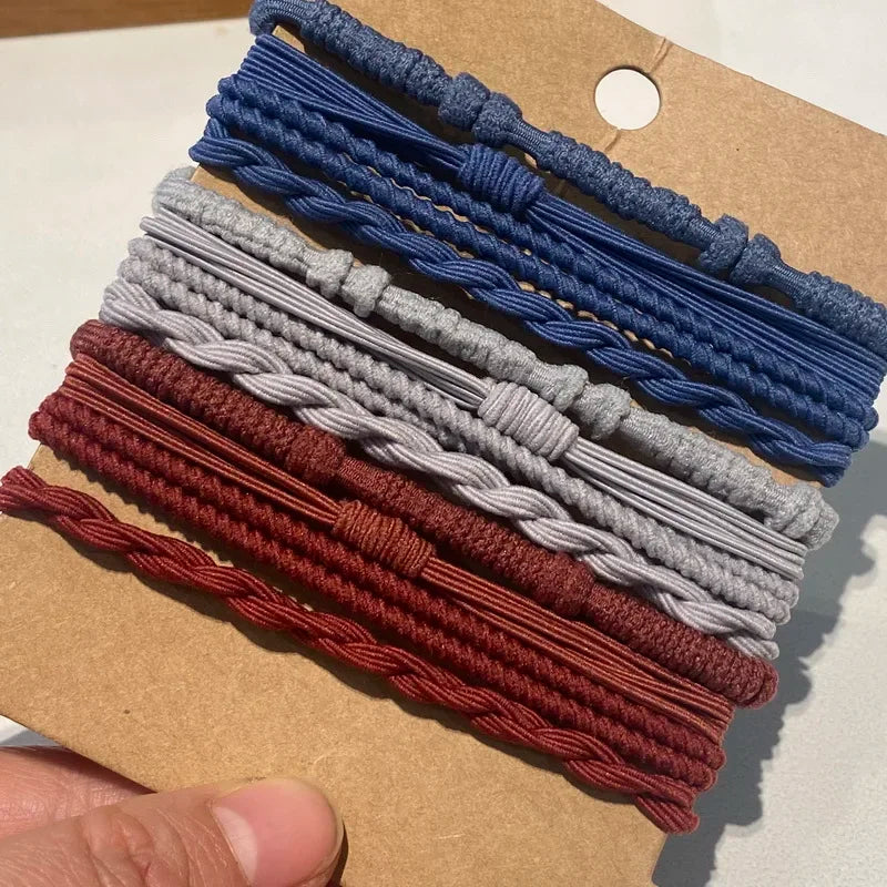 Eine Sammlung von Boho-Elastband-Haarbändeln in verschiedenen Blautönen, Grautönen und Weinrot auf einem Kraftpapier-Etikett.