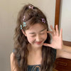 A young woman with long brown hair wears pink and blue star-shaped barrette clips in her hair.