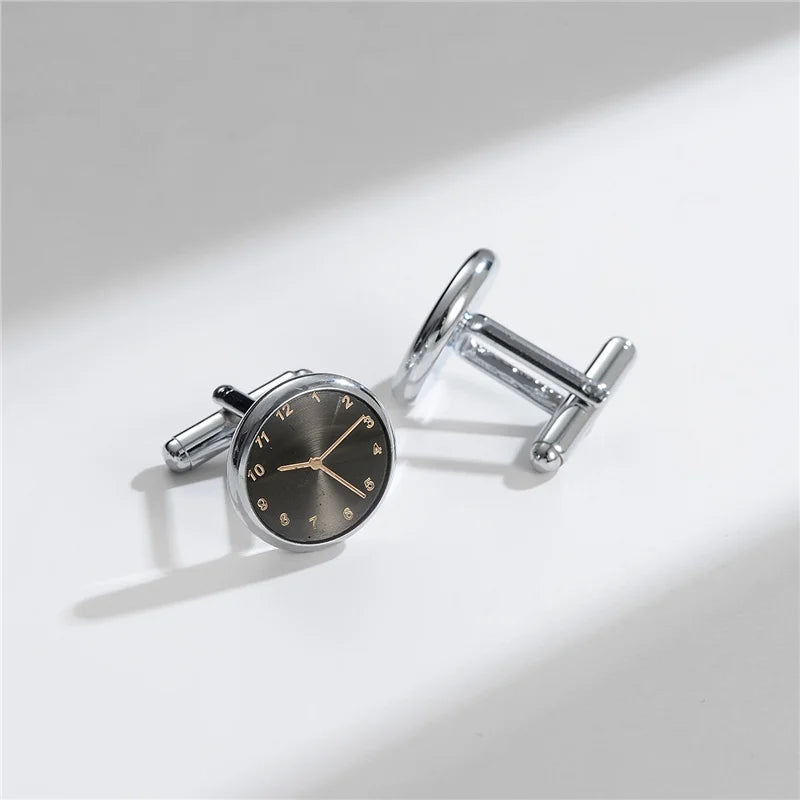 A close-up shot of elegant silver cufflinks with a round watch face design on a white background.