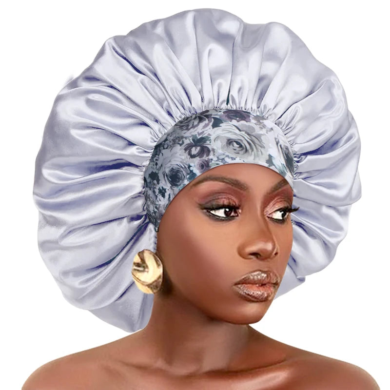 A woman wearing an extra large satin sleep bonnet with an elastic band, featuring a light purple and gray patterned fabric.