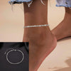 Silver snake chain anklet worn on a woman's ankle against a light background.