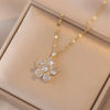 Un délicat collier en or avec un pendentif de fleur de zircon scintillante, présenté dans une boîte de couleur claire.