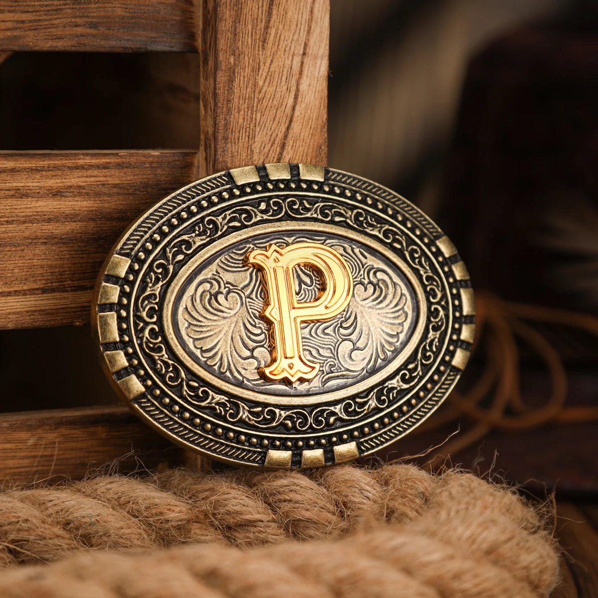 A vintage western belt buckle with a gold-toned design and intricate engraving resting on a brown textile.