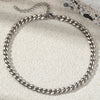 A silver multi-chain stainless steel anklet laid on a light textured surface.