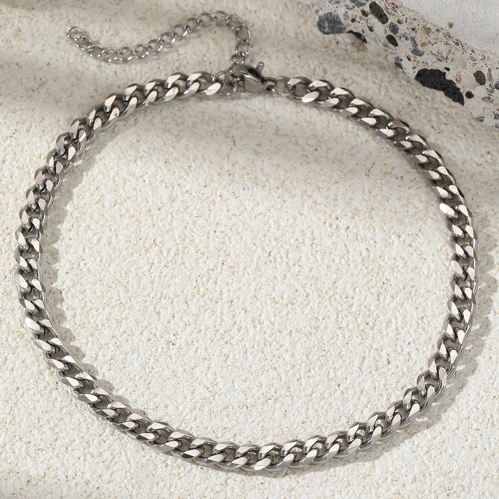 A silver multi-chain stainless steel anklet laid on a light textured surface.
