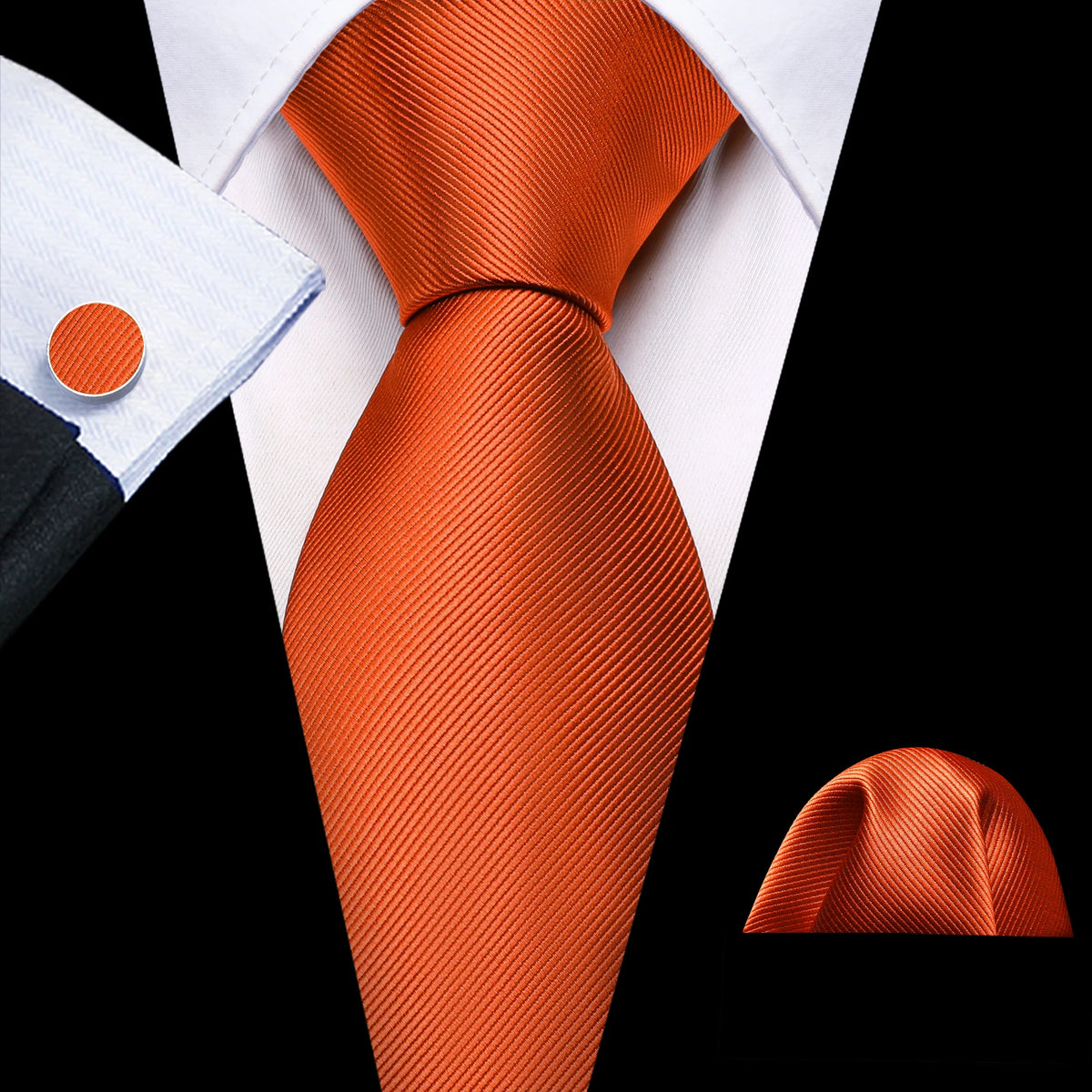 A close-up view of an orange silk jacquard tie and white dress shirt collar against a black background.