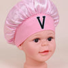 Pink A-Z letter sleep cap for kids with a satin toque and a large black V