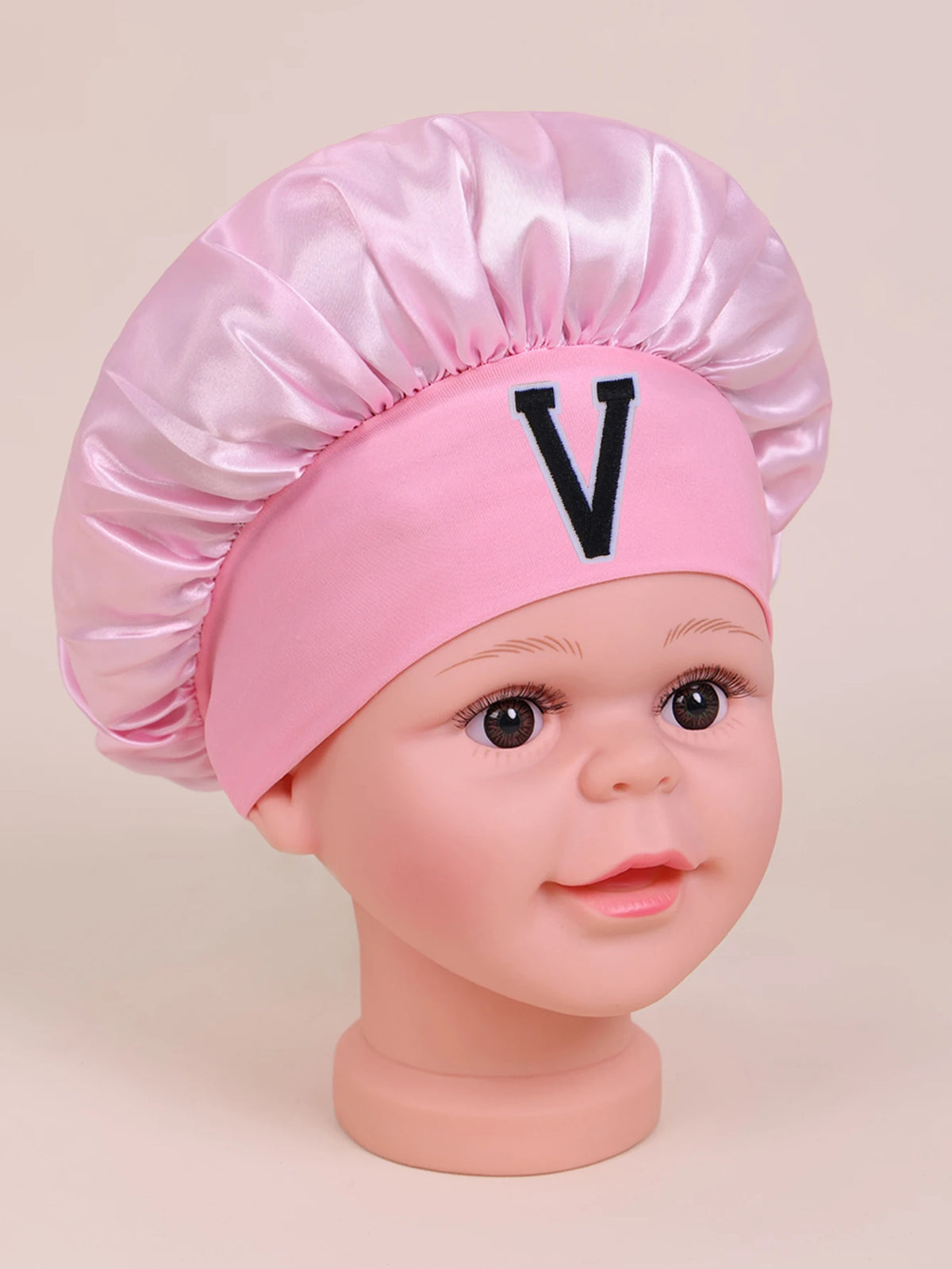 Pink A-Z letter sleep cap for kids with a satin toque and a large black V