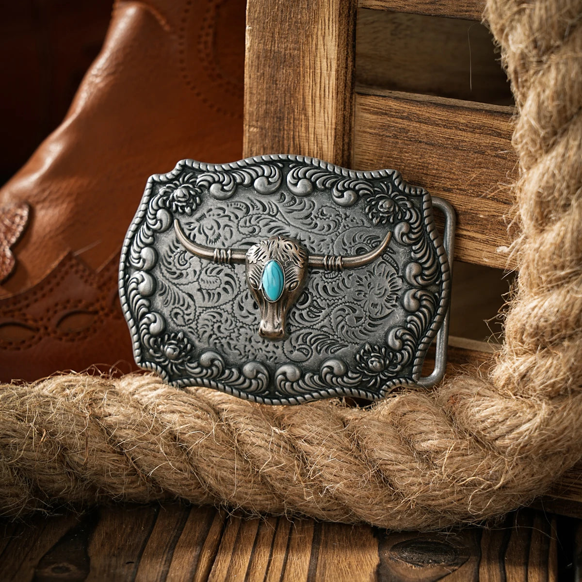 Boucle de ceinture en métal argenté avec tête de taureau détaillée et incrustation turquoise, posée sur un sac de jute.
