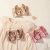 Light pink baby clothing featuring a top and a matching bow accessory.