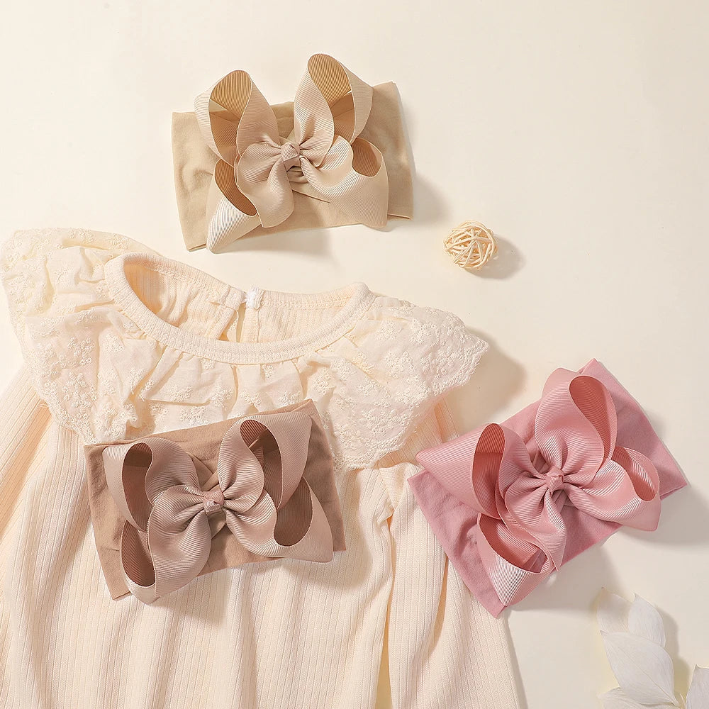Light pink baby clothing featuring a top and a matching bow accessory.