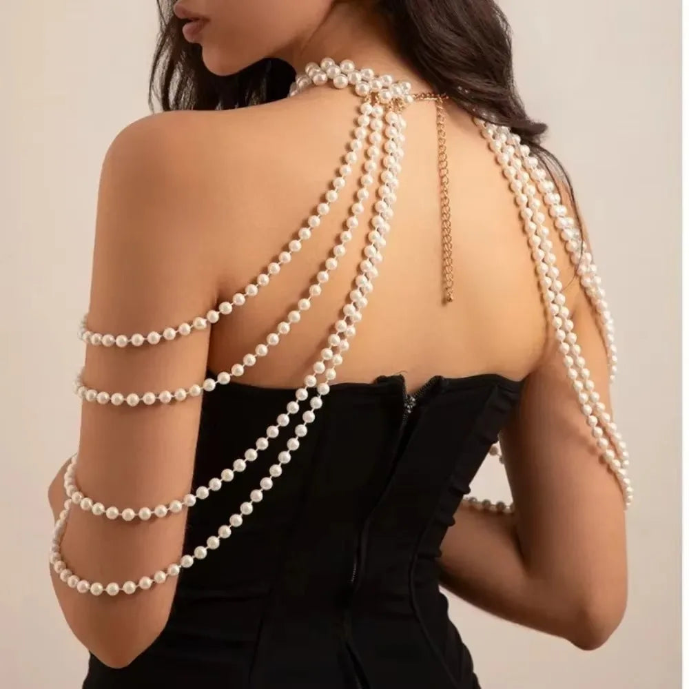 A woman wearing a black dress with multiple strands of imitation pearl necklaces draped across her back.