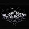 A sparkling crystal hair crown for women displayed on a black reflective surface.