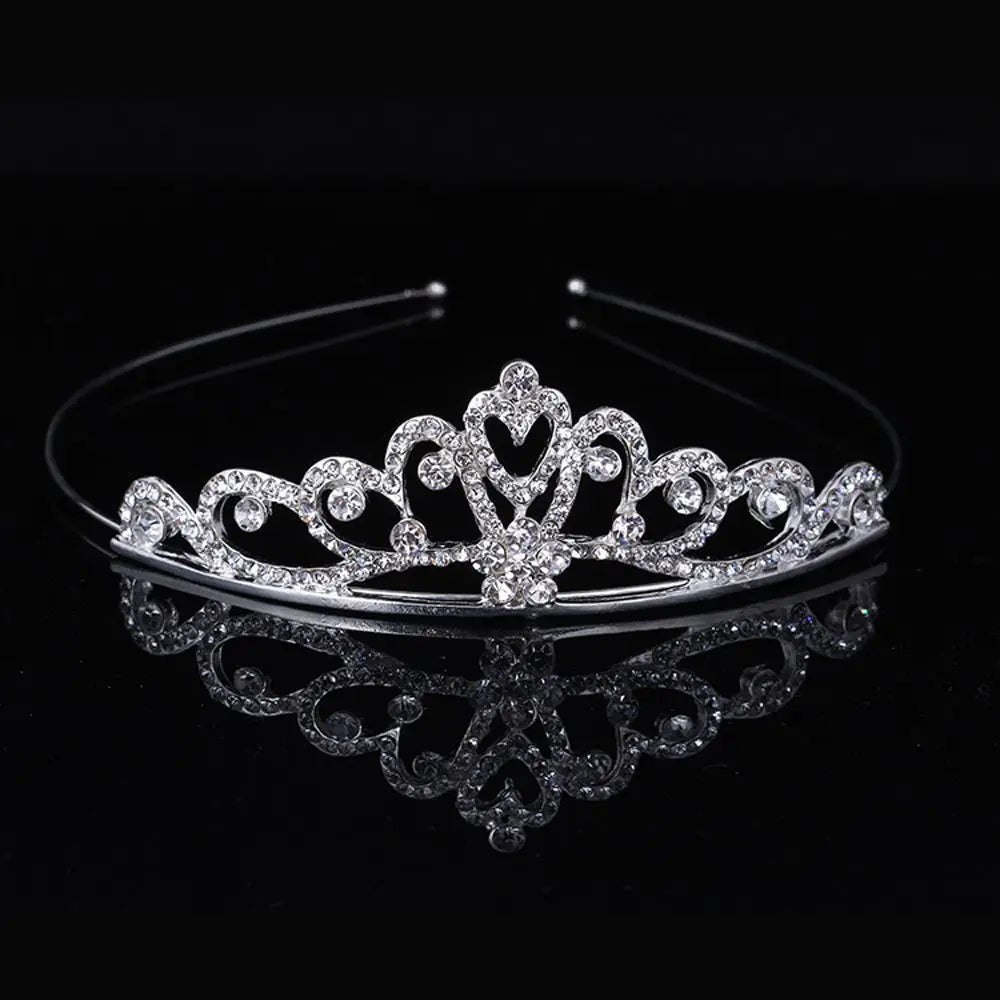 A sparkling crystal hair crown for women displayed on a black reflective surface.