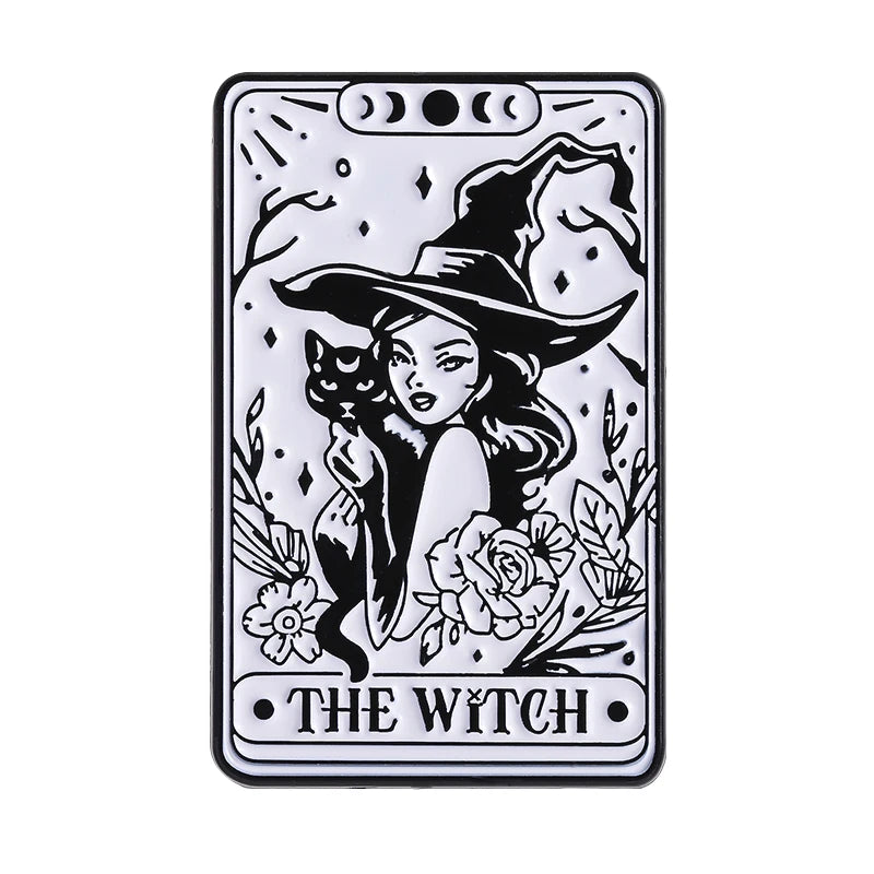 A black and white enamel pin featuring a witch with a pointed hat surrounded by floral elements.