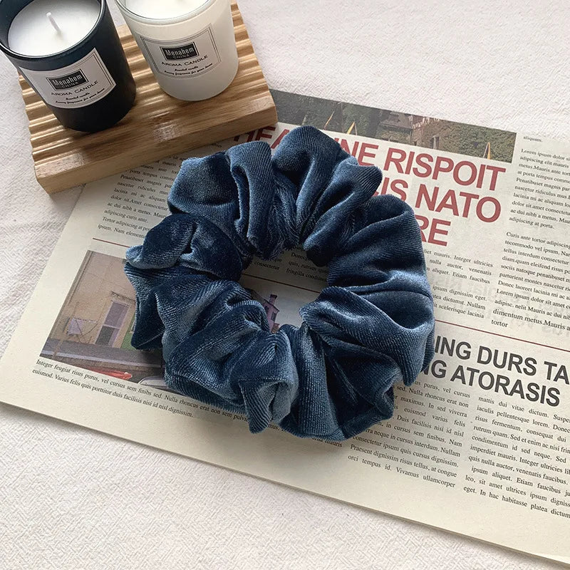 A dark blue heatless hair curling scrunchie is displayed next to candles on a wooden surface.