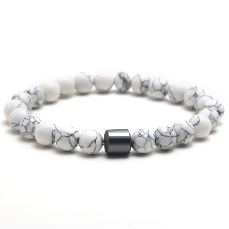 A bracelet made of white and black marble beads with a dark gray accent stone.